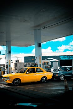 A yellow vintage Chevette at a gas station in Anápolis, Brazil, under a bright sky.