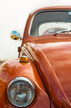 Close-up of a classic orange Volkswagen Beetle car with chrome details, perfect for vintage auto enthusiasts.
